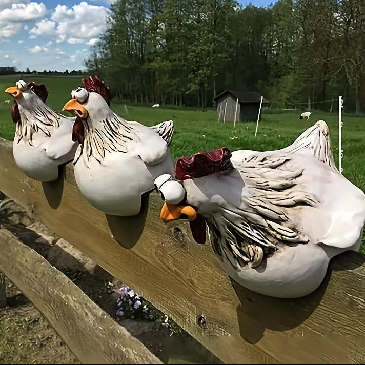 Three ceramic chicken figures on a wooden fence. 
